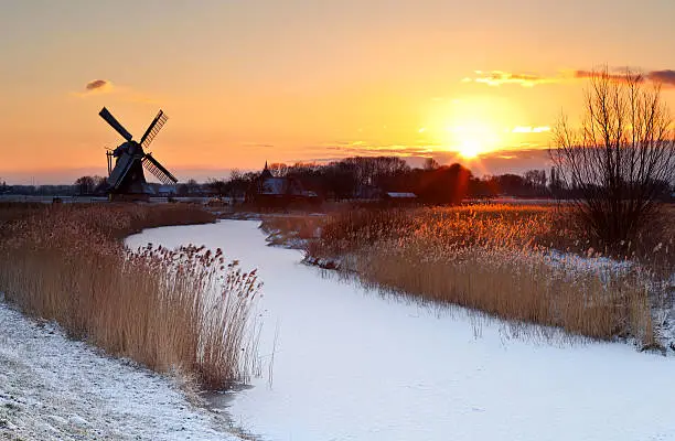dramatic sunrise by Dutch windmill during winter