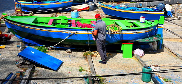 fisherman painting his boat in the small port of the Calabrian village 19 Sep 2023 Scilla Italy