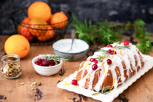 Traditional Christmas cake decorated with glaze, cranberries and rosemary