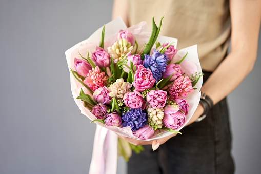 Sunny spring morning. Young happy woman holding a beautiful bunch of hyacinths and tulips in her hands. Present for a smiles girl. Flowers bouquet. High quality photo