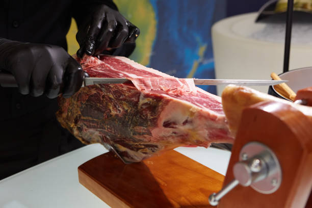istock Sliced dried chamon prosciutto. A man cuts a jamon, a warm toned image. Selective focus point. 1756386106