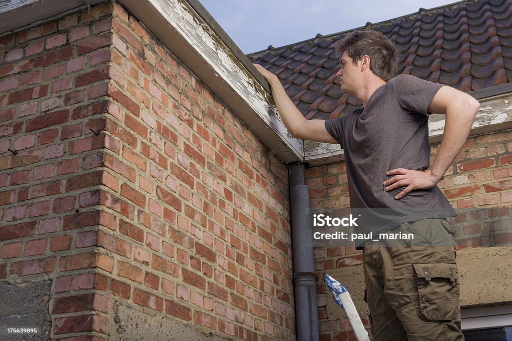 Giovane uomo ispezionando il tetto di una vecchia casa - Foto stock royalty-free di Esaminare
