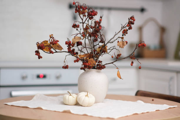 istock Autumn home interior- light cozy kitchen with ceramic vase and dry berries branches, pumpkin, linen napkin on round wooden table 1756403525