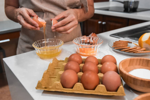 mains cassant un œuf pour faire de la crème pâtissière - break eggs domestic kitchen breaking photos et images de collection