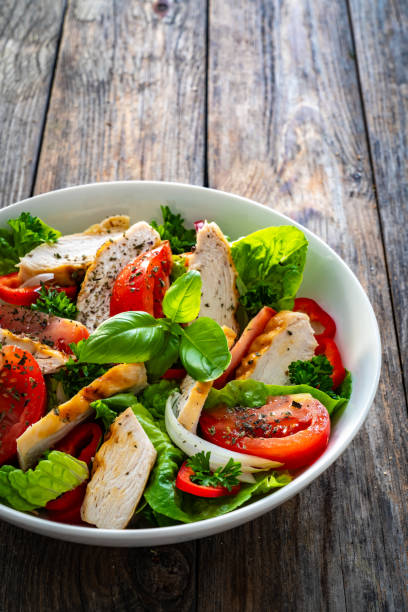 istock Caesar style salad  - fresh vegetables with grilled sliced chicken breast on wooden table 1756428925