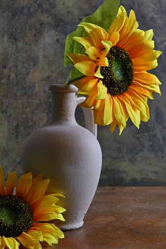 artificial sunflower in a white vase on a wooden background. Still life photography with low key. Women's day,mother's day,valentine's day