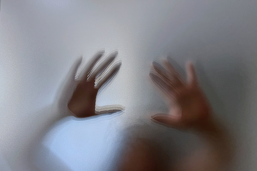 Hands behind blured glass