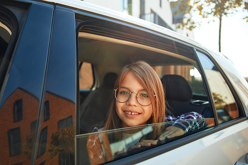 A family with daughter pretty child sitting in a car going on vacation for a weekend. Concept of recreation, tourism and travel.