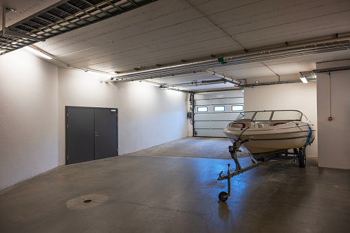 White motorboat on transport cradle in underground garage on parking lot.