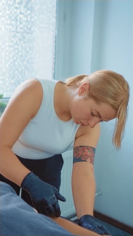 Master cosmetologist performs procedure for removing hair from hand of young woman using sugaring paste Vertical orientation