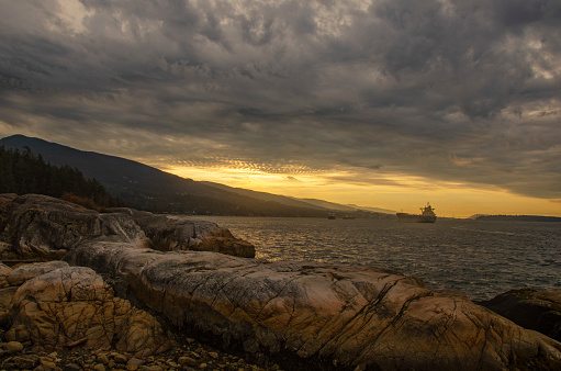Moody sky from the shore with some golden light peeking through at Lighthouse Park, West Vancouver, BC