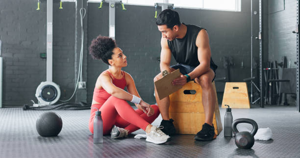 istock Personal trainer, woman and man with chart for exercise schedule, plan or check fitness progress in gym. Sports instructor, coach and checklist of people training for body health, workout or wellness 1756506987