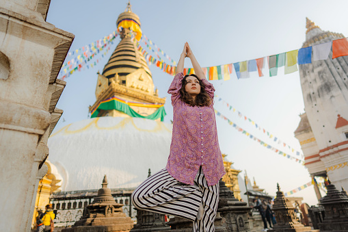 Serene woman  doing tree pose on the background of stupa
