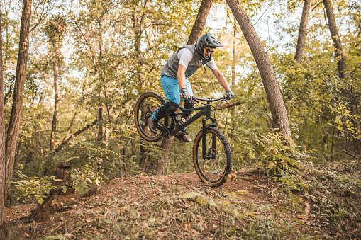Man enjoy his favorite hobby - downhill mountain biking. Downhill mountain biking is a style of mountain biking practiced on steep, rough terrain that often features jumps, drops, rock gardens and other obstacles