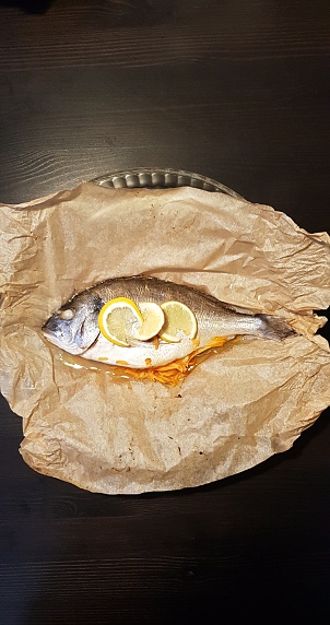 Seabream stuffed with butter, sliced lemon and grated carrots placed in a baking paper and roasted in oven and served at Glasgow Scotland England UK