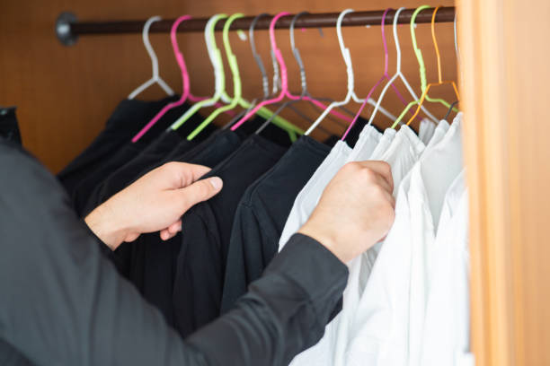istock Young man choosing between black and white shirts in his wardrobe, black and white clothes only, guy holding black and white shirts hanging in his wardrobe 1756534133