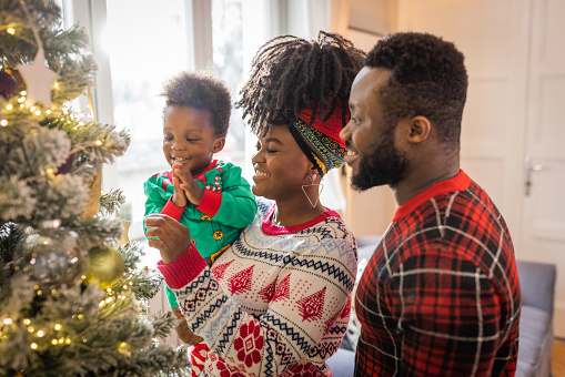 Young family celebrating Christmas at home. They are having fun and wearing Christmas sweaters.