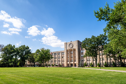 Main library building with the lawn in front of it. Trees are covered with colorful leaves during early fall.