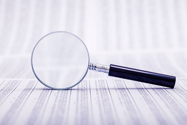 Magnifying glass laid on side atop coded papers stock photo