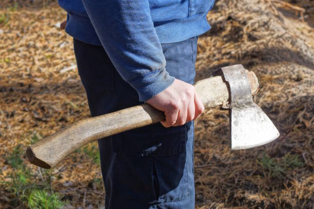 one male worker in blue clothes holds a gray ax in his hand on the street