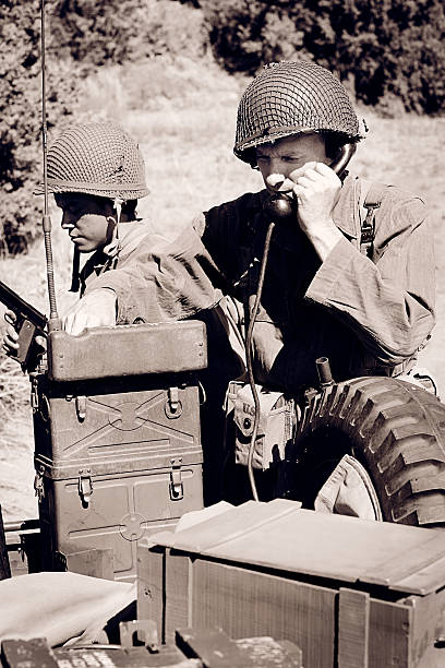 World War 2 Soldier Using a Field Telephone A WW2 soldier uses a field telephone in a combat zone. military invasion photos stock pictures, royalty-free photos & images
