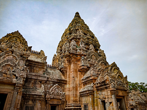 The Gopuram of the Shore Temple in Mahabalipuram or Mamallapuram, built in the 8th Century, between 700 and 728 AD, during the rign of the Pallava King Narasimhavarman II.  Declared a UNESCO World Heritage site in 1984, the temple is one of the oldest structural temples in South India. It survived the Tsunami of 2004. The sides display sand and wind errosion over 1300 years. Photo shot around noon against a blue sky with some clouds.  No people; copy space.