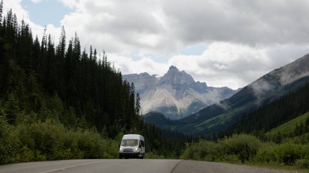 camping-car sur une autoroute dans les rocheuses canadiennes - driving motor home forest banff national park photos et images de collection