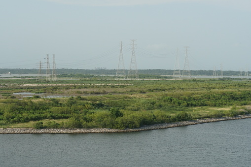 High electric pylons on a green field observed from the container terminal of the Port of Houston.