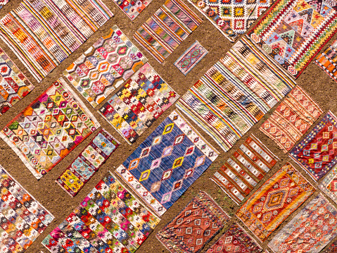 sewing, patchwork and fashion concept - beautiful colorful quilts were neatly folded and stored in several rows in height for storage, sale of finished textile stitched products on white background