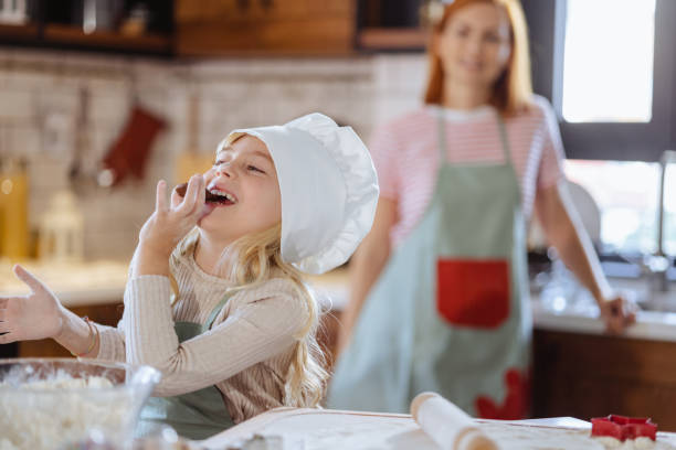 istock Little girl with chef's hat eating sweets in the kitchen 1756656527