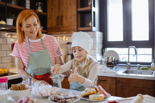 istock Cute girl is helping her mother in the kitchen 1756660741