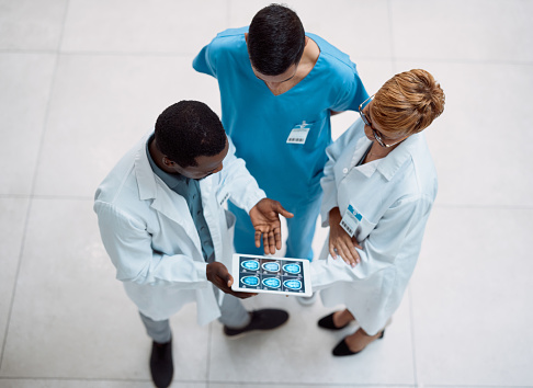 Doctor, tablet and meeting in healthcare above on screen for research, anatomy or surgery analysis. Medical professional team holding touchscreen and brain x ray display in collaboration or planning