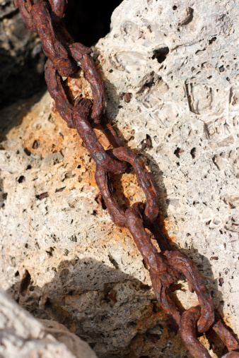 Old industrial chain links in stones at the harbor