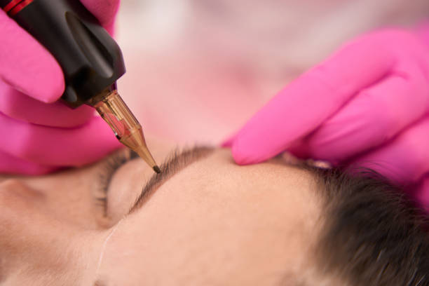 istock Master in pink gloves makes a tattoo of womans eyebrows 1756675387