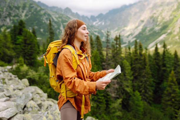 istock Beautiful woman traveler with a yellow backpack, holds a map. 1756678590