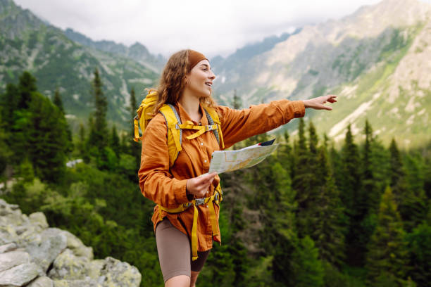 istock Beautiful woman traveler with a yellow backpack, holds a map. 1756678593
