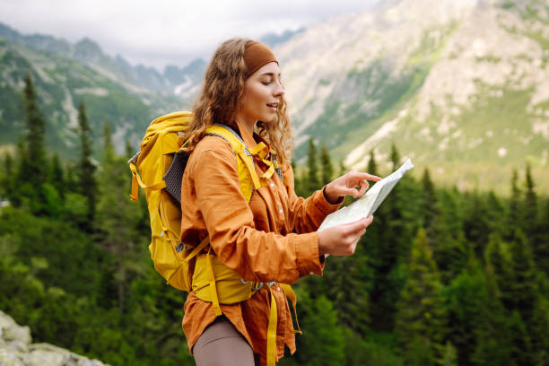istock Beautiful woman traveler with a yellow backpack, holds a map. 1756678594