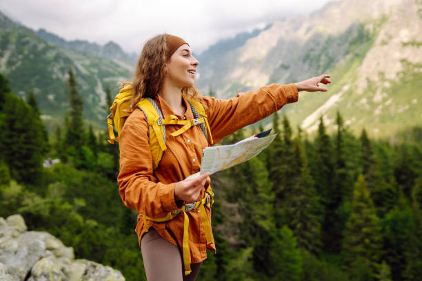 istock Beautiful woman traveler with a yellow backpack, holds a map. 1756678595