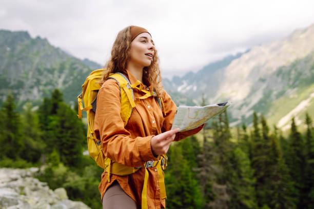 istock Beautiful woman traveler with a yellow backpack, holds a map. 1756678596