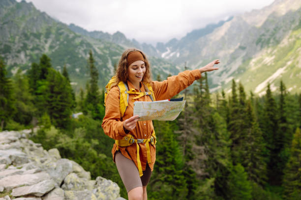 istock Beautiful woman traveler with a yellow backpack, holds a map. 1756678601