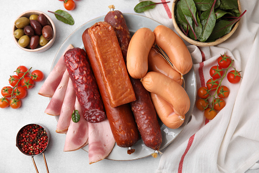 Different types of tasty sausages and ingredients on white table, flat lay