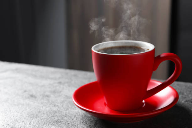 istock Red cup with hot steaming coffee on grey table indoors, space for text 1756697130