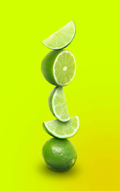 istock Stacked whole and cut limes on yellowish green background 1756697644