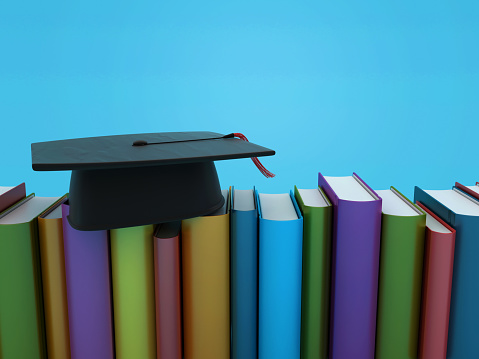 Teenage boy wearing cap and gown holding diploma in schoolyard