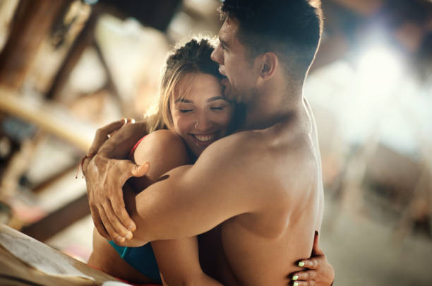 Closeup of a mid 20's couple relaxing at a beach bar and showing some affection.