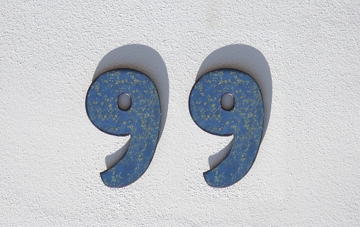 House number 99. Painted iron over whitewashed wall. Houses with personality concept
