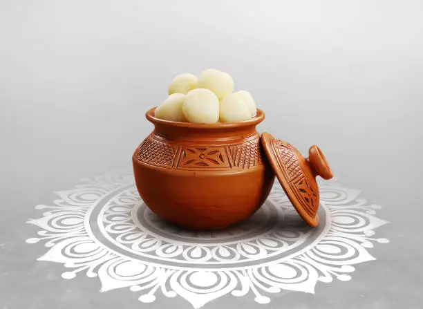 Indian traditional Assorted Sweets Rasgulla on Hari with Alpona Floor Background.