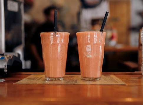 Two glasses of pink smoothie on a bar counter