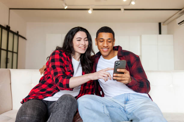 istock young multiracial couple using smartphone at home on comfortable sofa, african american man with woman 1756764733