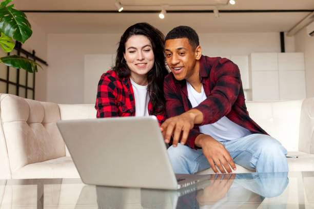 istock young multiracial couple sitting on comfortable sofa and looking into laptop at home 1756764745